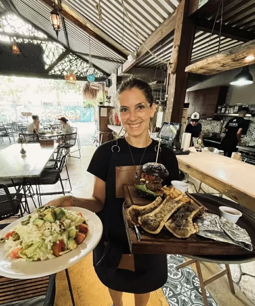 Mesera mostrando platillos de un restaurante de carnes de Playa del Carmen