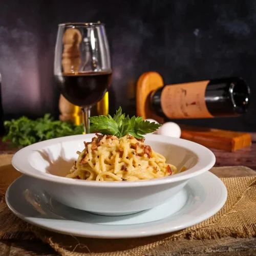 Platillo de comida italiana acompañado de una copa de vino en el restaurante luna rossa