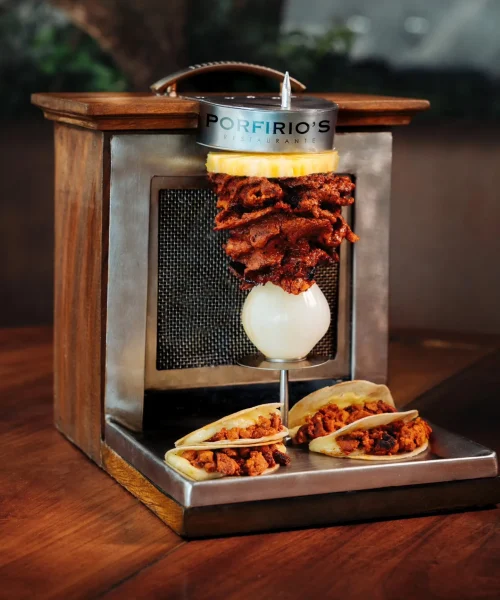 Mini trompo de pastor acompañado de tacos ideal para cenar en restaurante porfirios